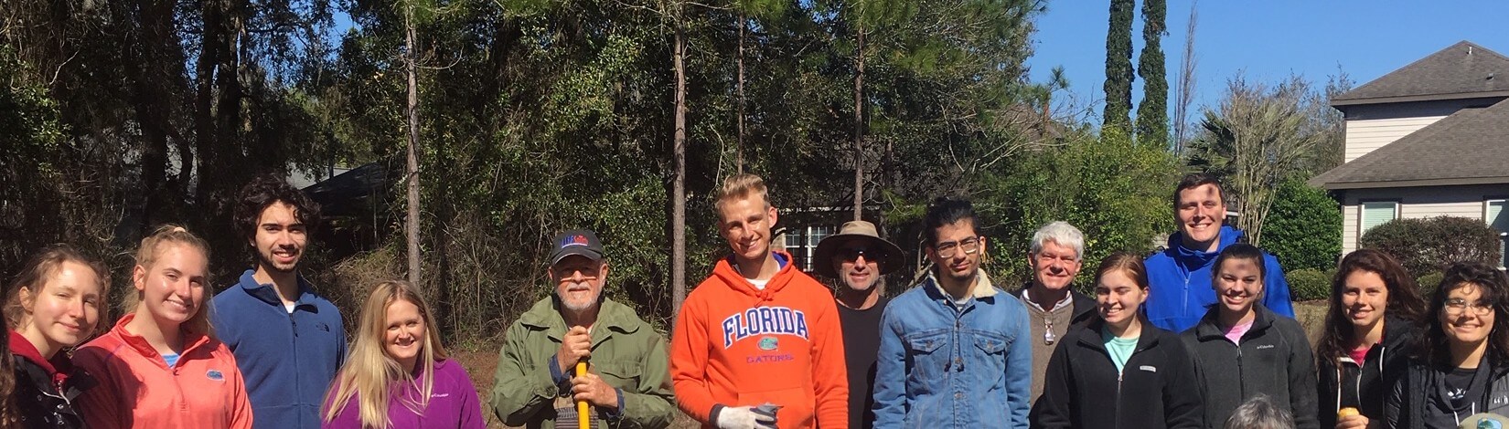 a group of people working outside in front of a home on a sustainable living project