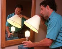 man changing out the light bulb from a lamp inside a residential home
