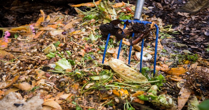 close up of a pitchfork mixing compost and food scraps